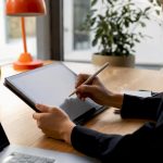 Hands marking glossary on tablet in neutral workspace